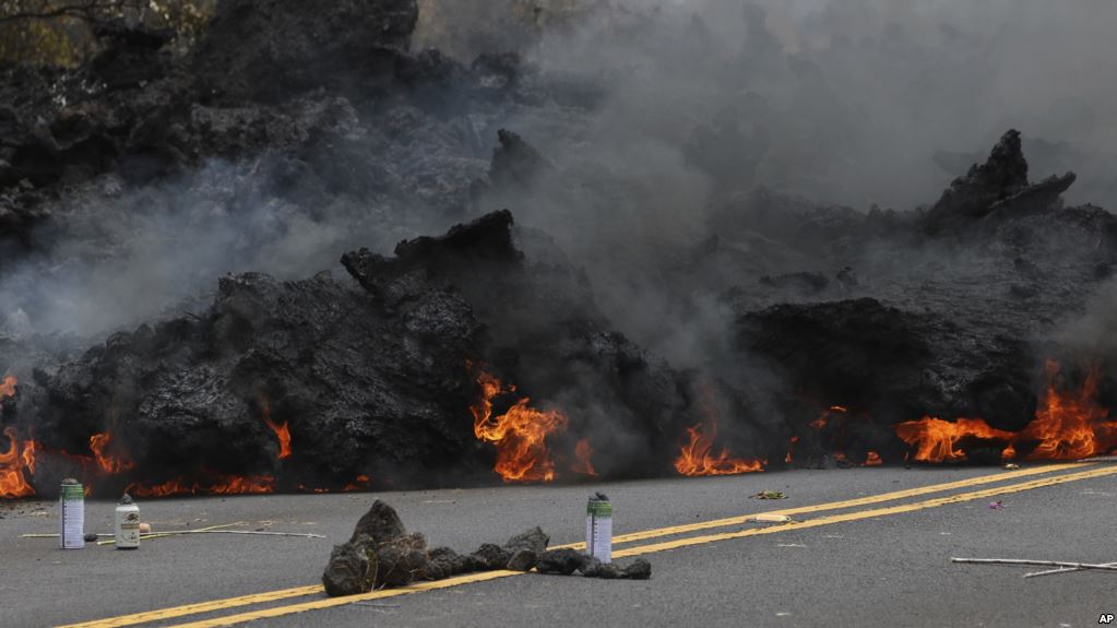 Lava burns across a road in the Leilani Estates subdivision on Saturday, May 5, 2018 near Pahoa, Hawaii. (AP Photo/Caleb Jones)