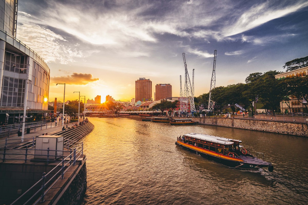 CLARKE QUAY, SINGAPORE - APRIL, 2015: Sunset at Clarke Quay with a boat passing by
